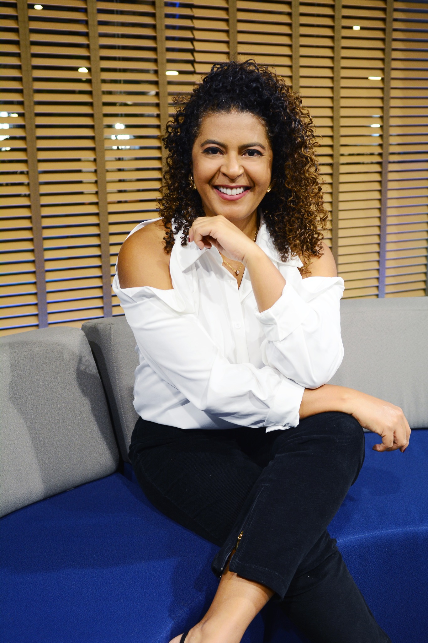Heide Vieira sentada no sofá, sorrindo